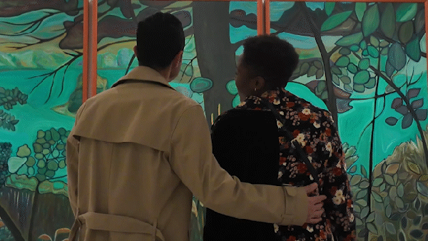 A happy couple smiles and looks at art together