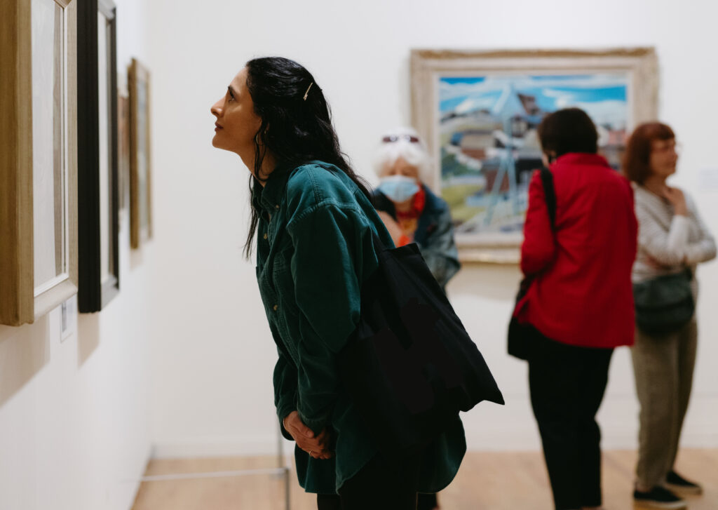 A woman leans in to look at a painting.
