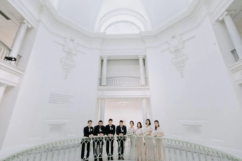 A wedding party of 4 men and 4 women stands in the Gallery's 3rd Floor Rotunda