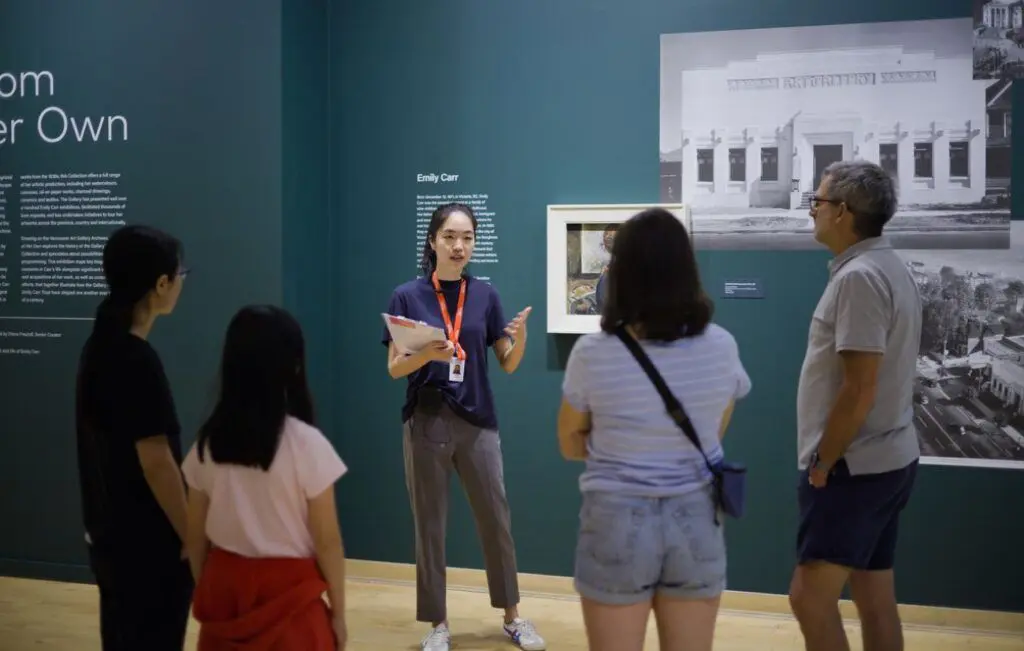An Art Educator giving a tour of Emily Carr: A Room of Her Own to a family of four.