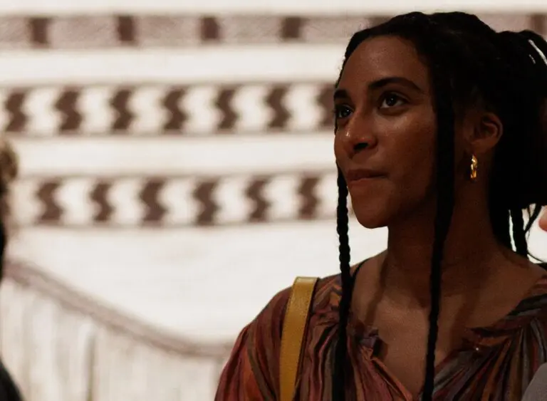 A Black woman looks inspired as she visits the Gallery. An Indigenous weaving is visible behind her.