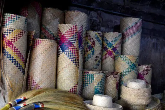 Rolled up, colourful handwoven mats and hats