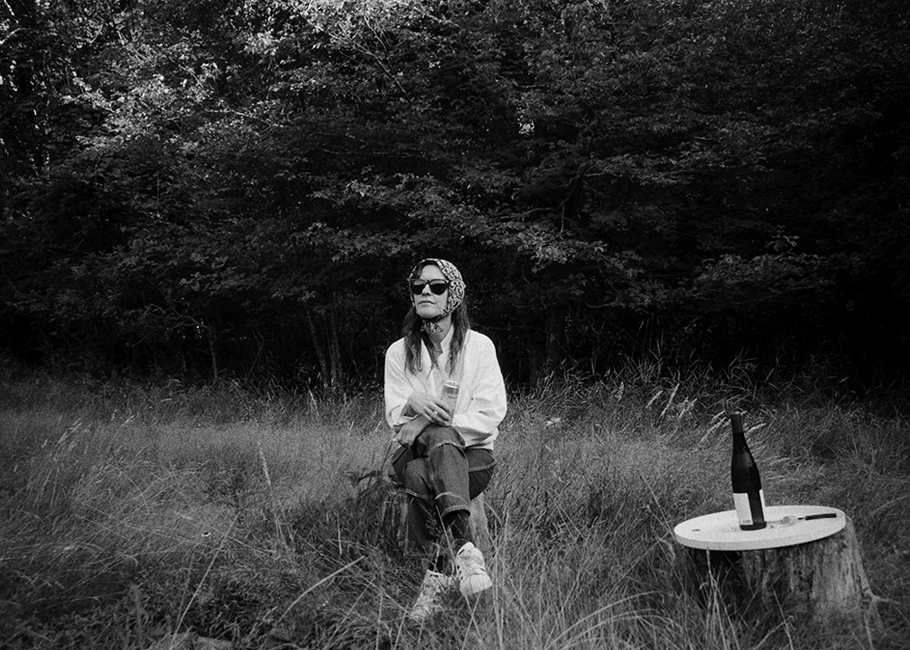 Black-and-white photo of artist Lucy Raven in a field