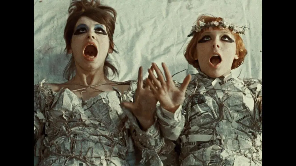 Still from Věra Chytilová's 1966 film Daisies, two women lying on their backs with shocked faces.