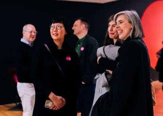 Gallery visitors in looking at art and smiling.