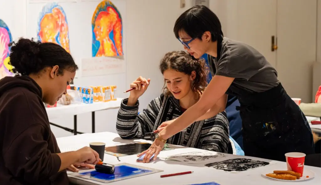 An instructor guides two teens through a drawing exercise.