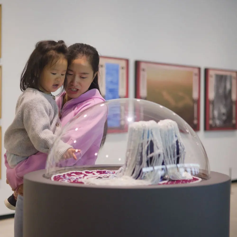 Mother and daughter looking at Shelley Niro: 500 Year Itch in the Gallery.