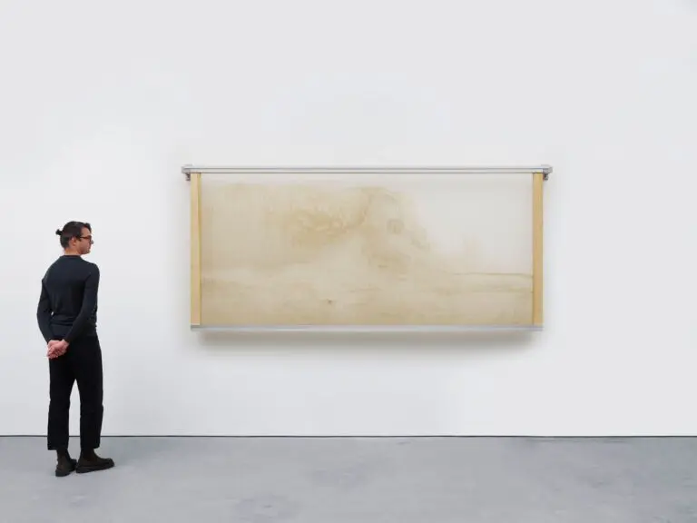 A man stands next to Lucy Raven's artwork Depositions, a series of non-representational “images” mounted and installed on wood and aluminum armatures